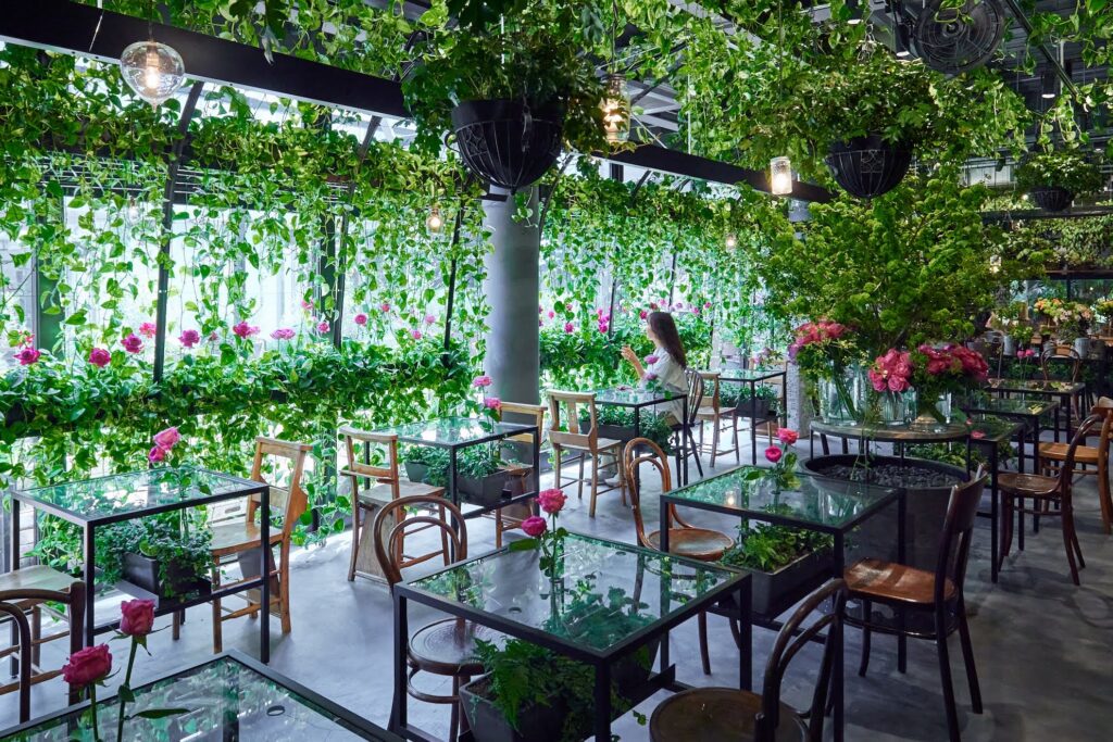 Aoyama Flower Market TEA HOUSEの緑と花に覆われた店内。水の流れを使った水音の演出も設計されている